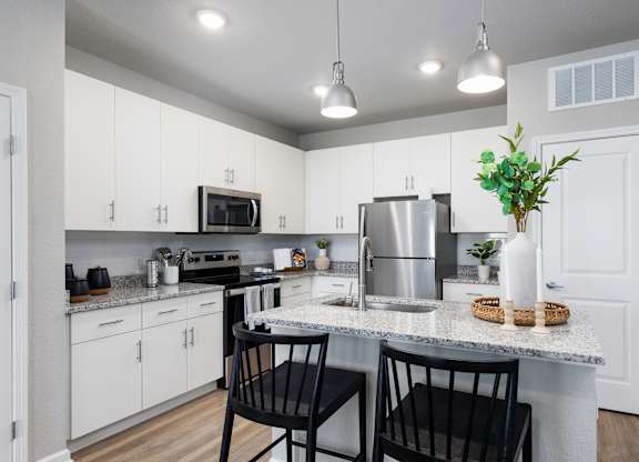 an open kitchen with white cabinets and a granite counter top