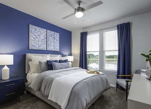 a blue and white bedroom with a bed and a ceiling fan