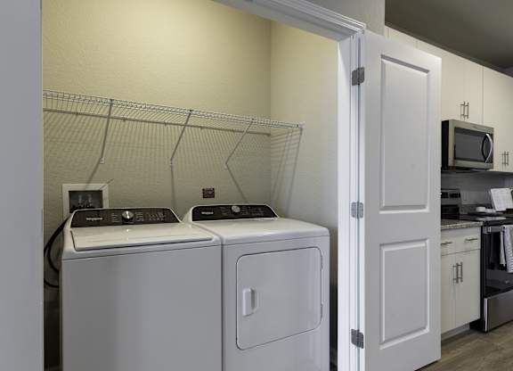 a washer and dryer in a laundry room with a kitchen in the background