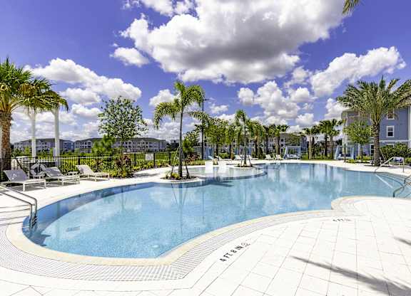 A large outdoor swimming pool surrounded by palm trees.