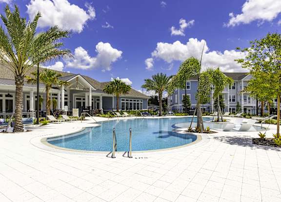A swimming pool surrounded by palm trees and a white tiled patio.