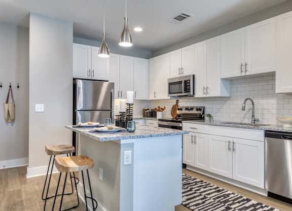 A kitchen with a white island and stainless steel appliances.