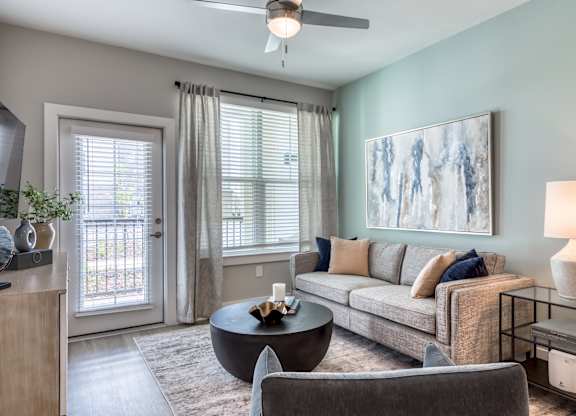 A living room with a grey couch, a coffee table, and a painting on the wall.