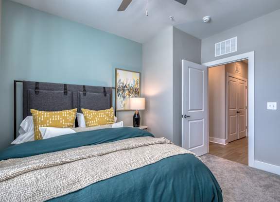 A bedroom with a bed, pillows, and a ceiling fan.