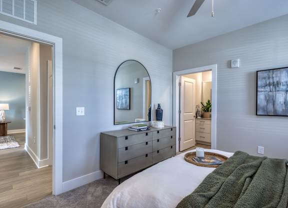 A bedroom with a large bed and a dresser with a mirror above it.