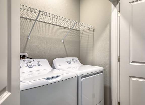 Two white washing machines in a laundry room.