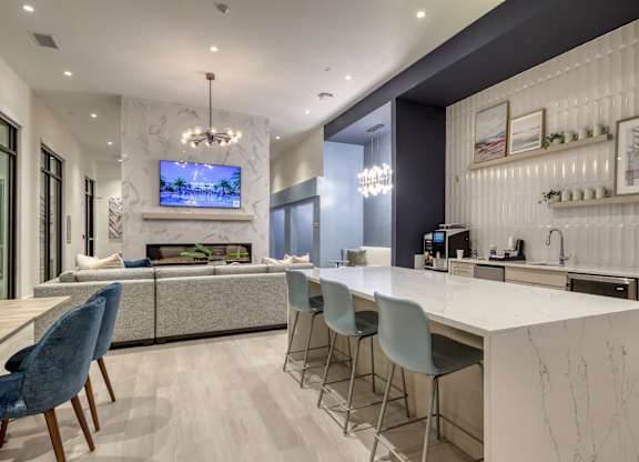 A modern kitchen with a white countertop and blue chairs.