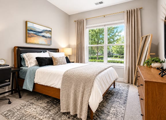 A bedroom with a large bed and a painting on the wall.