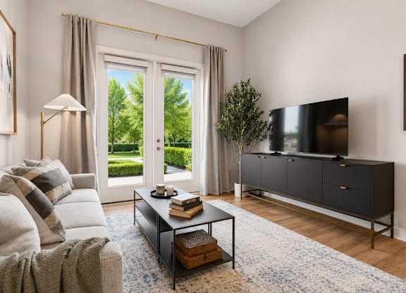 A living room with a grey sofa, a black cabinet, and a large window with curtains.