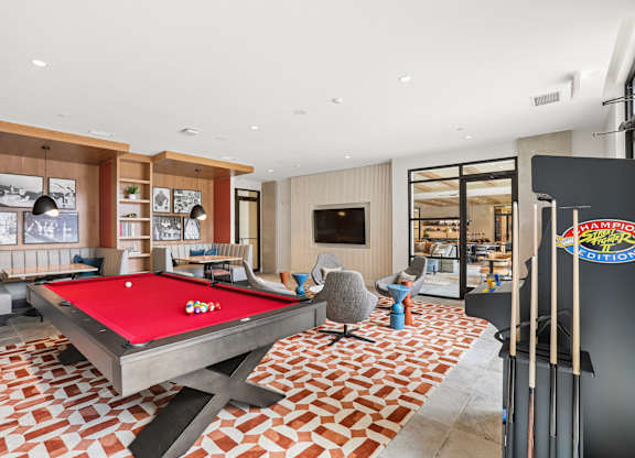 A pool table is in the middle of a room with a red cloth.