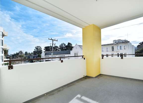 A yellow column stands in the middle of a white-walled, open balcony.