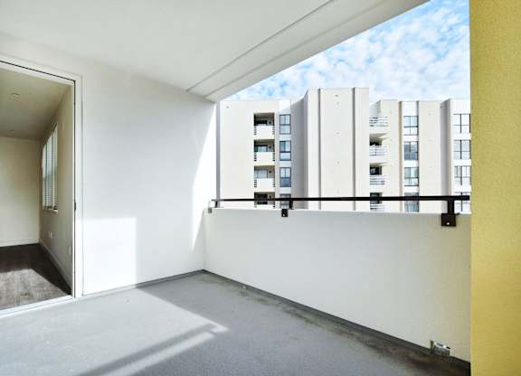 an empty room with a balcony overlooking an apartment building