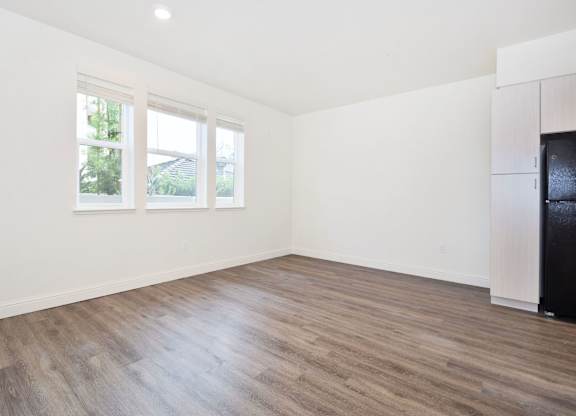 A room with wooden floors and white walls, with a black appliance on the right side.