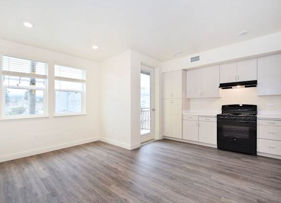 an empty kitchen with white cabinets and a black stove and refrigerator