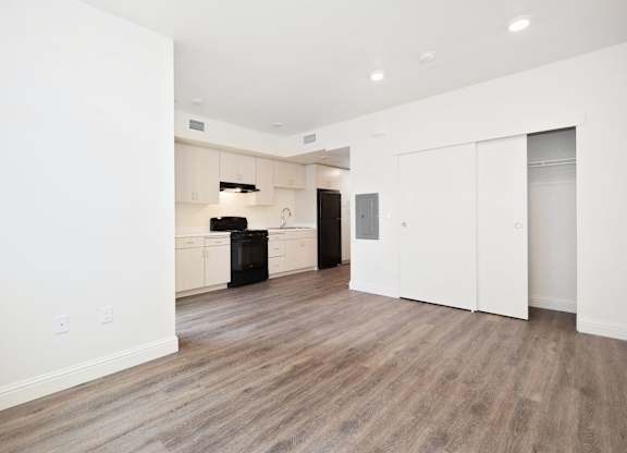 A spacious room with wooden flooring and white walls.