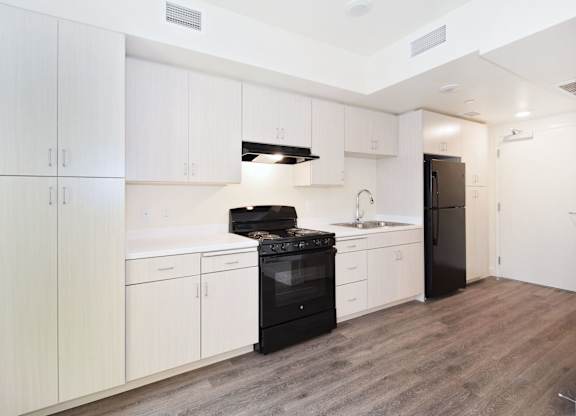 A kitchen with white cabinets and a black stove top oven.