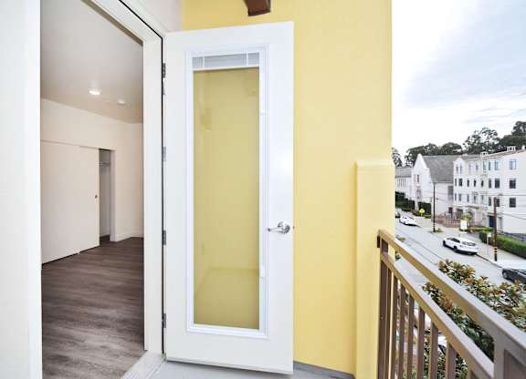 A white door with a glass panel is open to a balcony.