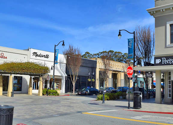 A street view of a shopping area with a stop sign.