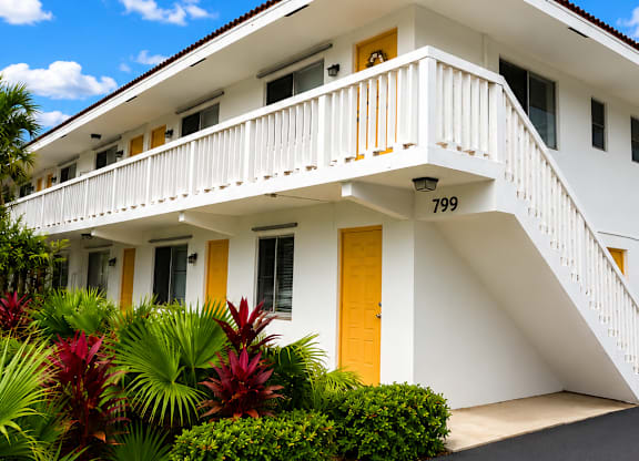 A white house with a yellow door and a balcony.