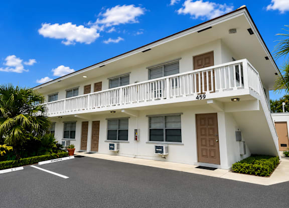A white two-story house with a balcony on the second floor.