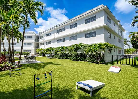 A white building with a green lawn in front.