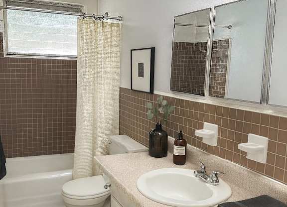 A bathroom with brown tiles and a white toilet.