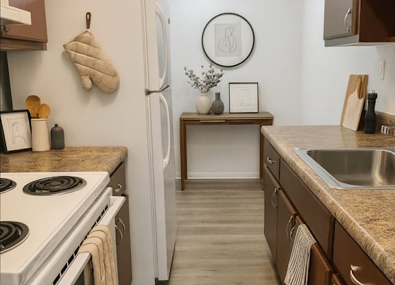 A kitchen with a white stove top oven and white refrigerator.
