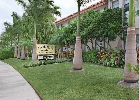 A sign for Camino Verde Federal Apartments is in front of a building with a row of palm trees.