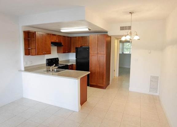 A kitchen with a black refrigerator and wooden cabinets.