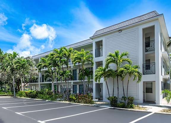 A white building with a parking lot in front of it.
