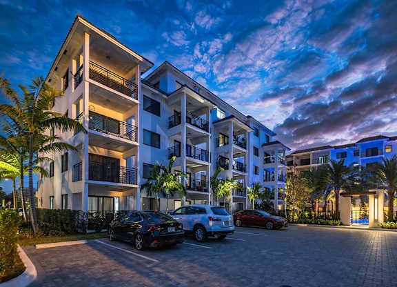 an apartment building at night with cars parked in front of it