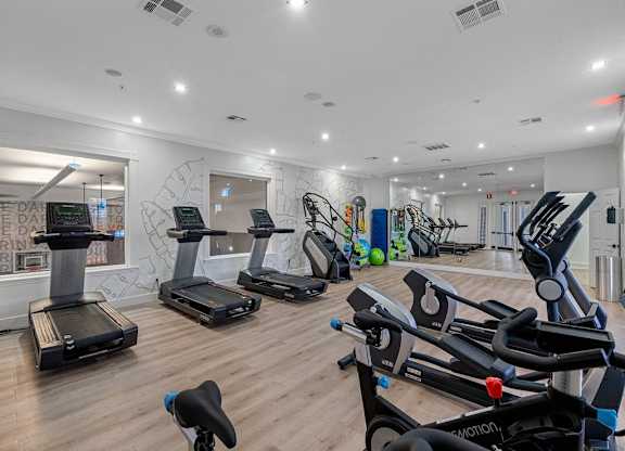 the gym has plenty of cardio equipment and a wall mural of graffiti