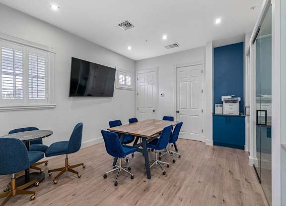 a conference room with a table and chairs and a tv