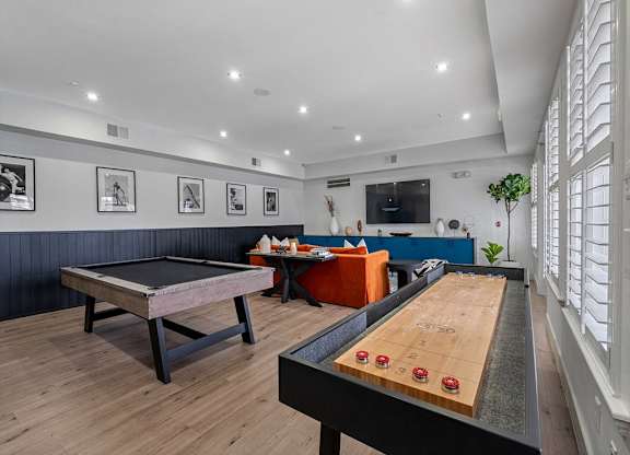 a game room with a shuffleboard table and a pool table