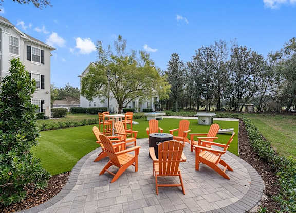 an outdoor patio with orange chairs and a fire pit