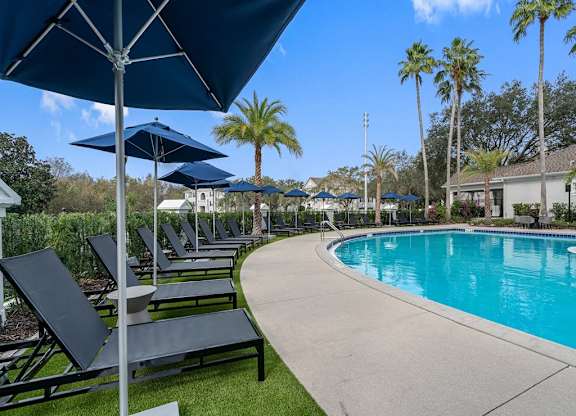 a swimming pool with lounge chairs and umbrellas at the resort