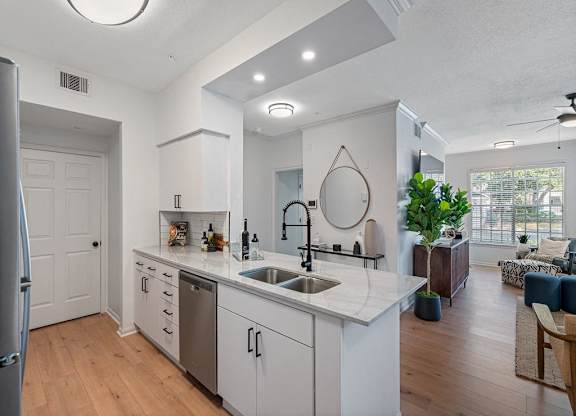 an open kitchen and living room with white cabinets and a sink