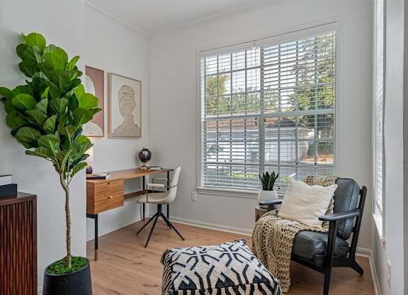 a living room with a couch and a desk and a window