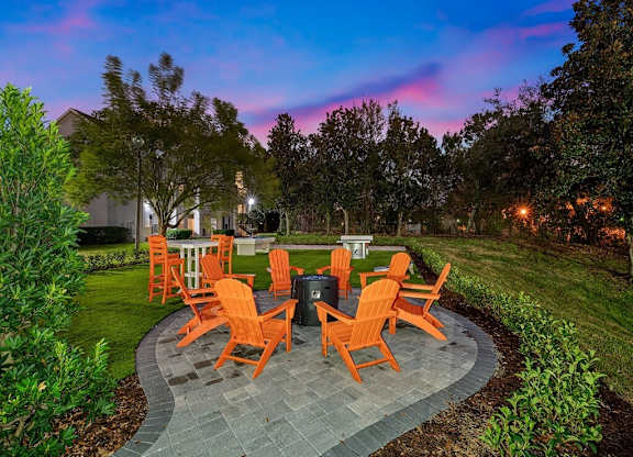 a patio with orange chairs and a fire pit