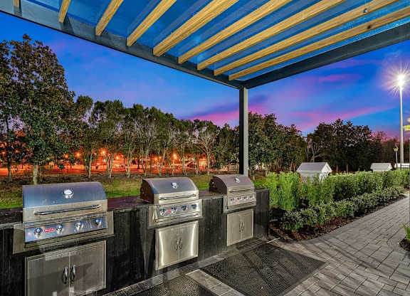 a group of stainless steel gas grills under a blue and yellow roof