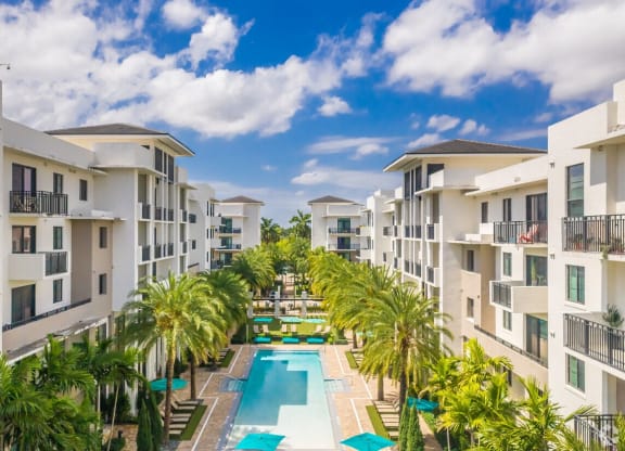an aerial view of an apartment complex with a pool and palm trees