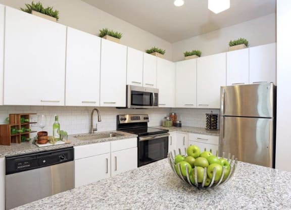 a kitchen with white cabinets and a bowl of fruit