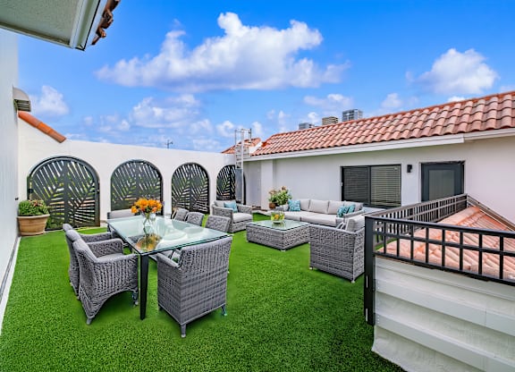 A patio with a table and chairs is surrounded by a white wall.