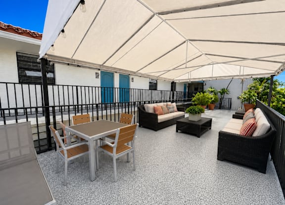 A patio with a table and chairs under a white canopy.