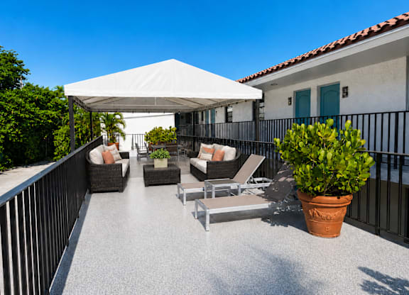 A patio with a white canopy and grey furniture.