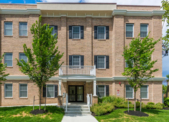 a brick building with a balcony and trees in front of it at Greenway Village Apartments, Metuchen