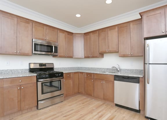 a kitchen with wooden cabinets and stainless steel appliances at Greenway Village Apartments, New Jersey
