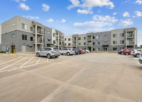 A parking lot in front of a multi-story apartment building.