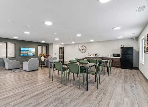 A modern dining room with a wooden floor and a large table surrounded by chairs.