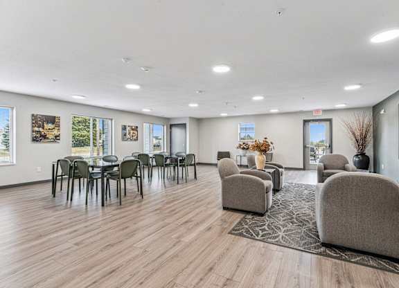 A spacious room with wooden floors and a variety of seating options.